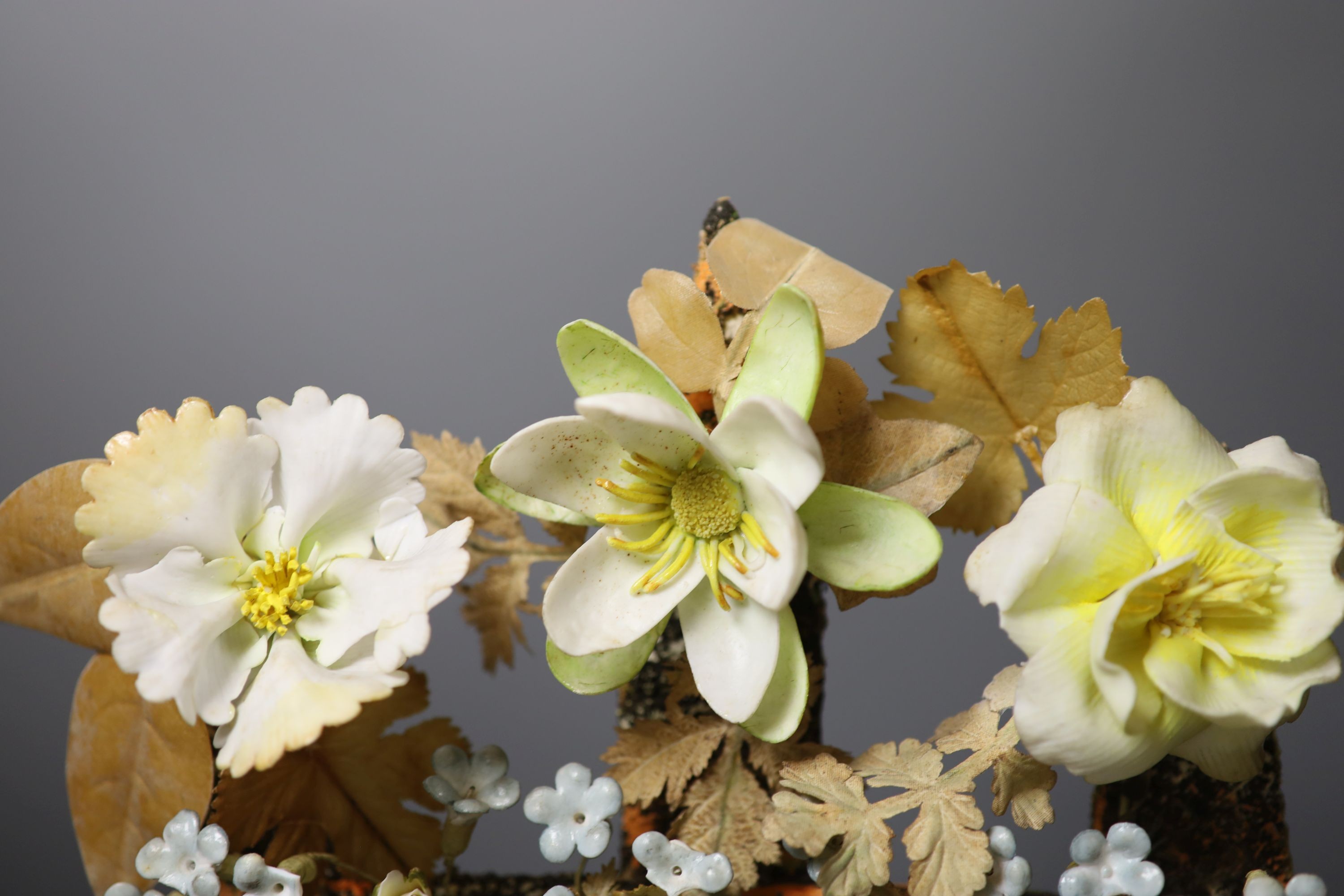 A late 19th century model of porcelain flowers under a glass dome 52cm total height